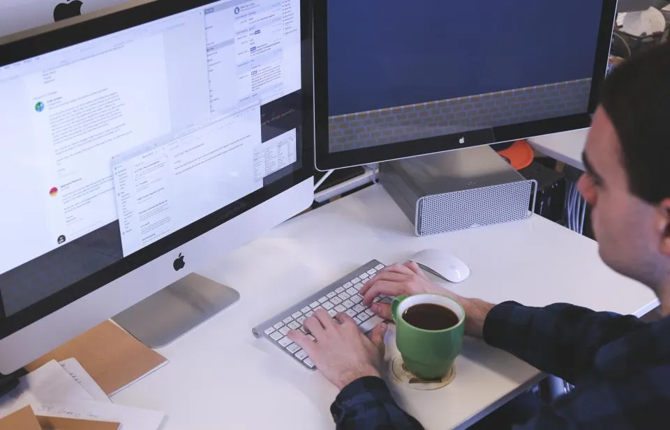 A person working at a desk beside a cup of coffee